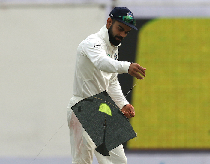 Virat Kohli deals with a stray kite on the field